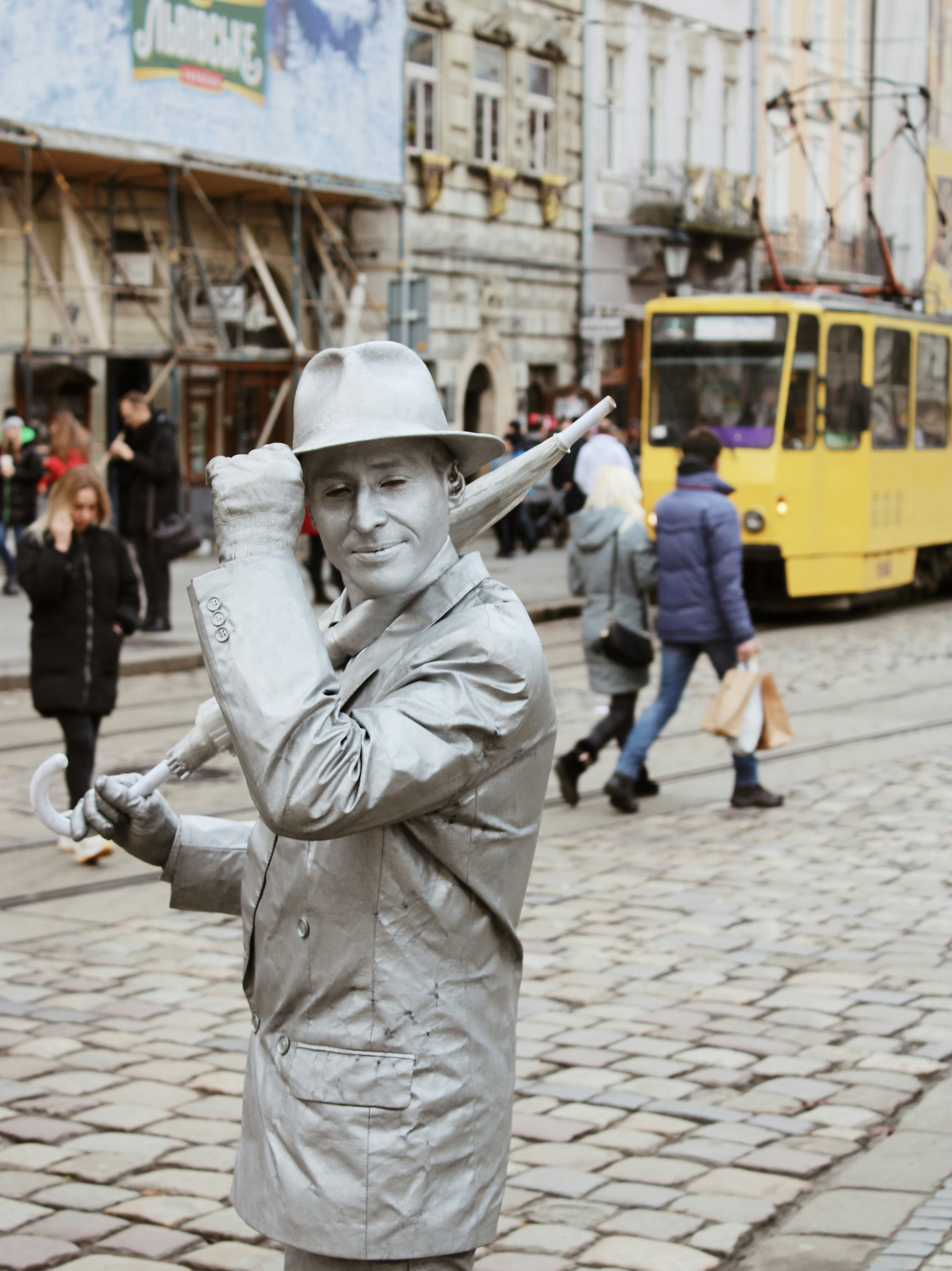 man in gray coat and white hat standing on gray brick pavement